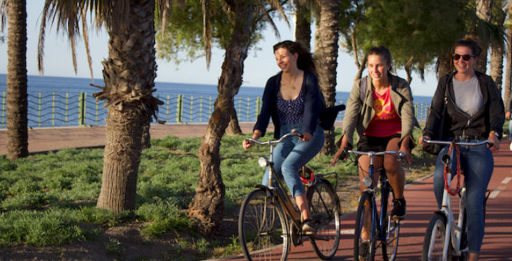 alumnos de intercambio montando en bici junto al mar